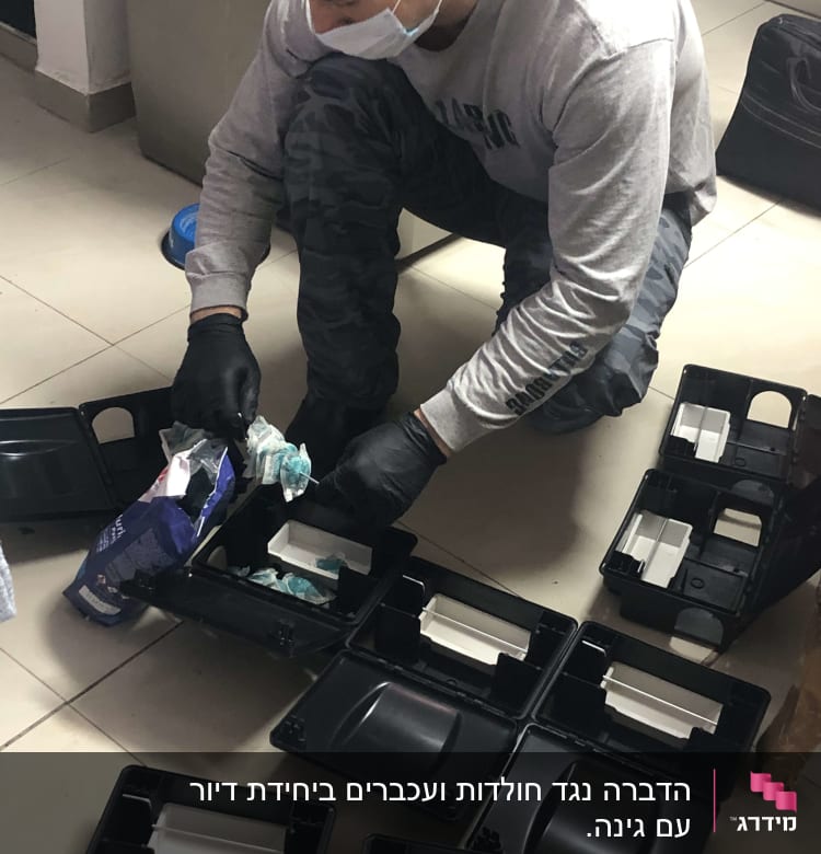 אדם עם מסכה וכפפות מכין מלכודות מזיקים על הרצפה